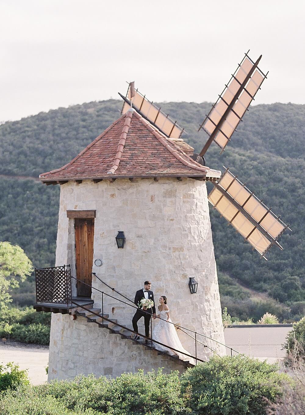 bride and groom walk up the steps of a French windmill at Cal-a-Vie Spa - Jacqueline Benét