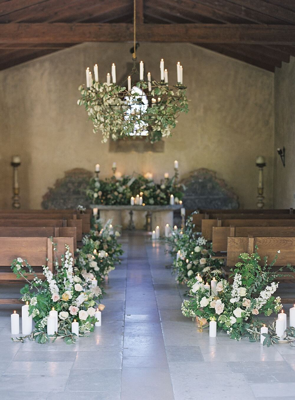 cal-a-vie wedding chapel with romantic florals lining the aisle and candlelit alter - Jacqueline Benét