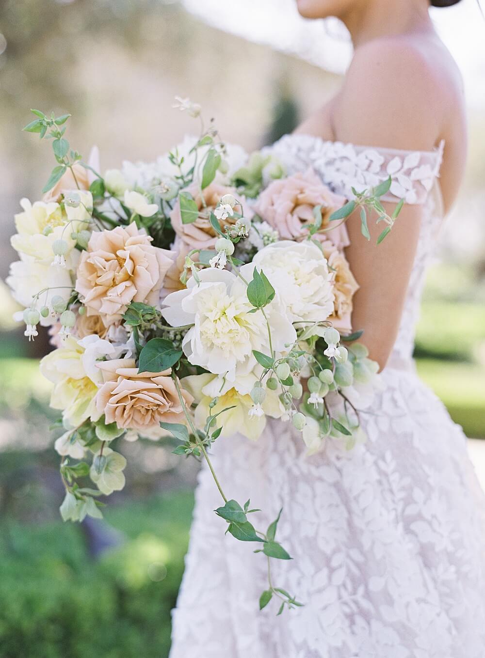 peach cream and green bridal bouquet held by bride in floral applique dress - Jacqueline Benét Photography