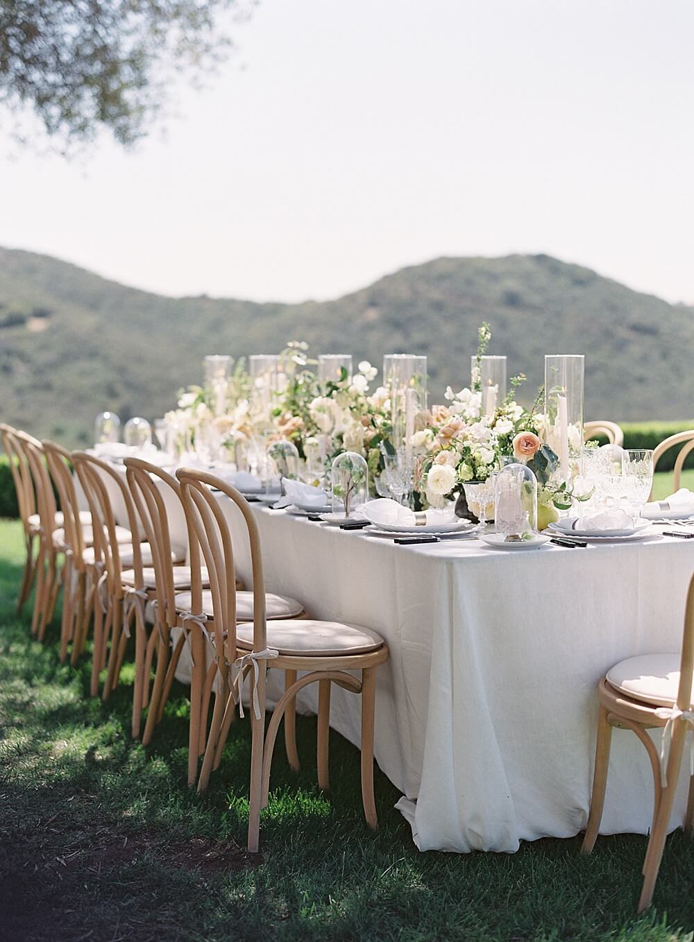 Al fresco outdoor wedding reception with cream peach pear and light wood tabletop at Cal-a-vie - Jacqueline Benét Photography