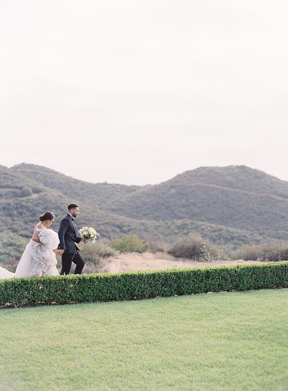 bride and groom walk with mountains in the background at cal-a-vie wedding - Jacqueline Benét Photography