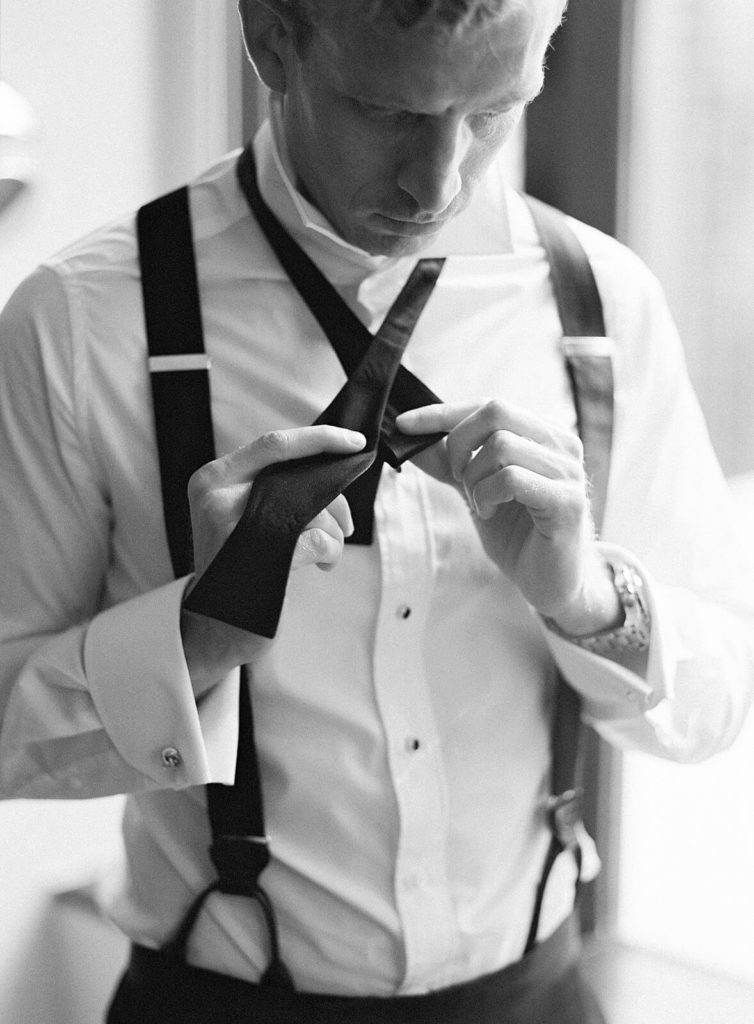 black and white photo of groom getting ready with classic black bowtie - Jacqueline Benét Photography