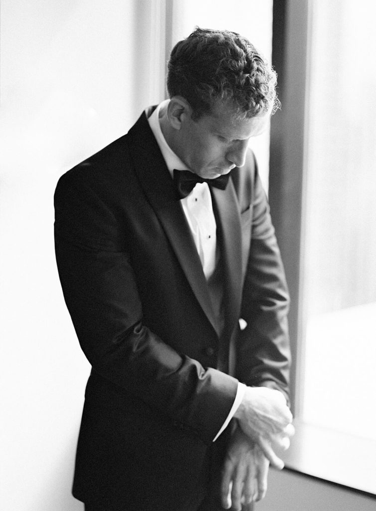 black and white photo of groom getting ready in classic black tux