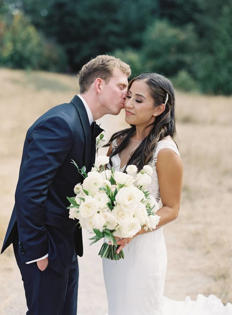 Groom kisses bride's cheek at Discovery Park in Seattle - Jacqueline Benét Photography
