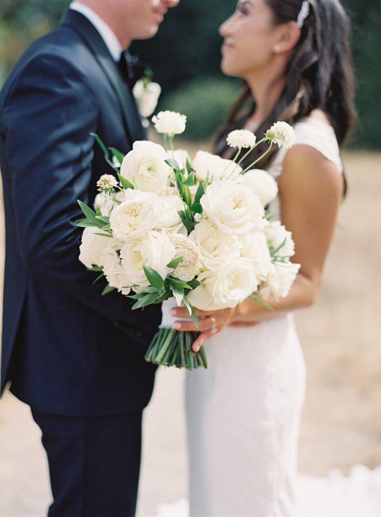 White bridal bouquet with bride and groom in the background at Discovery Park  - Jacqueline Benét Photography