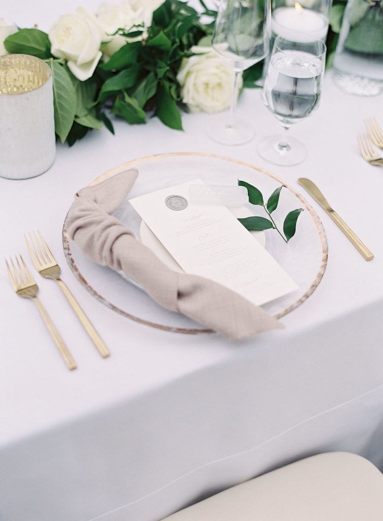 White menus with gold and clear chargers and modern flatware for white wedding reception tabletop  -Jacqueline Benét Photography