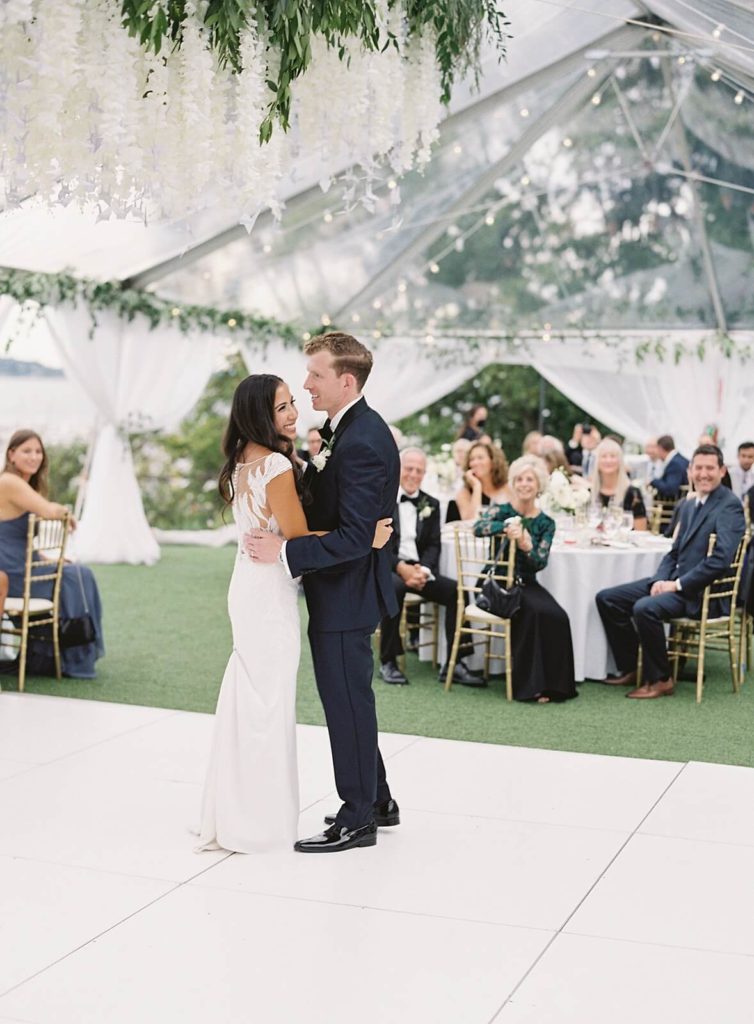 First dance at Admirals House wedding under clear tent and white floral hanging centerpiece - Jacqueline Benét Photography