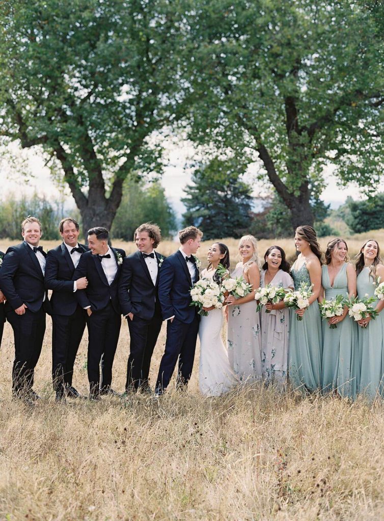 Bridal party laughs as the wind blows during photos at Discovery Park in Seattle - Jacqueline Benét Photography