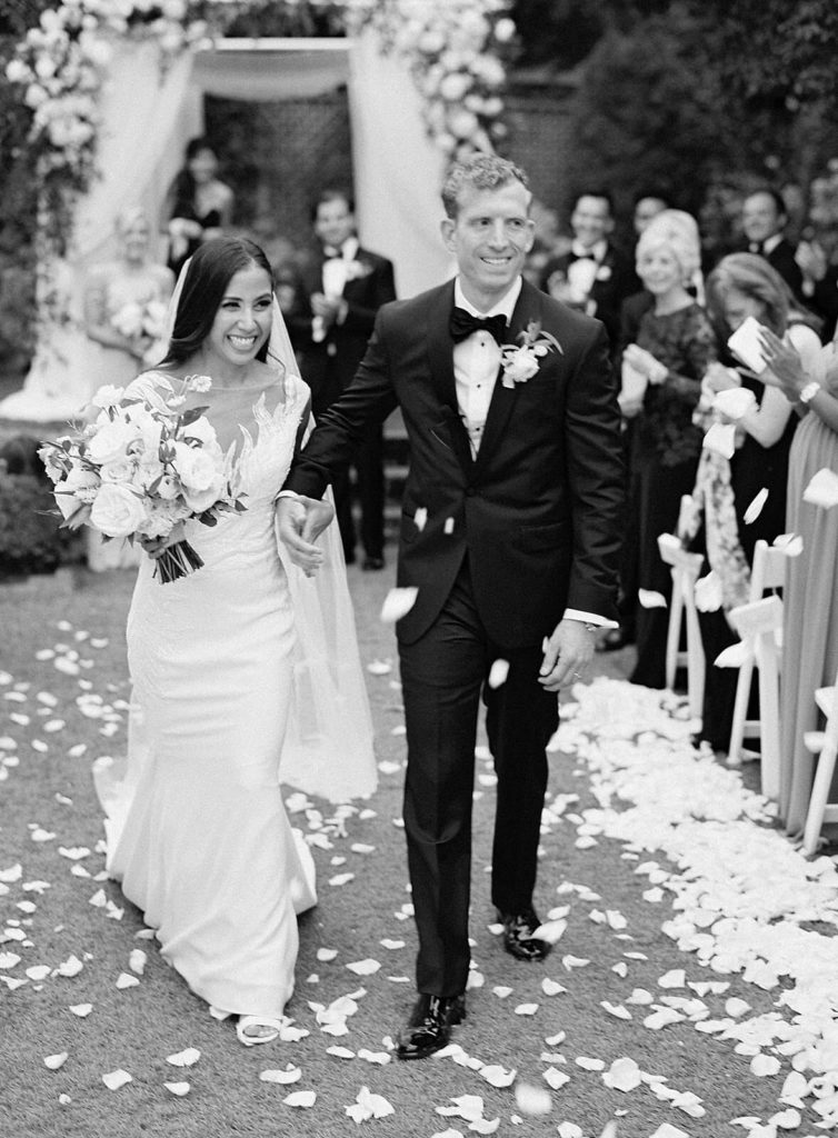 Black and white photo of bride and groom waling up the aisle at Admirals House - Jacqueline Benét Photography