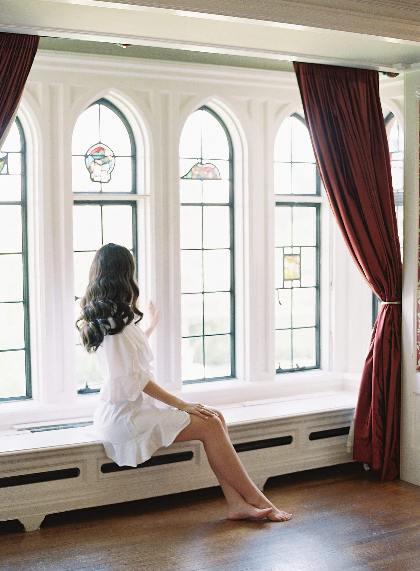 Bride looks out window of Thornewood Castle - Jacqueline Benét Photography