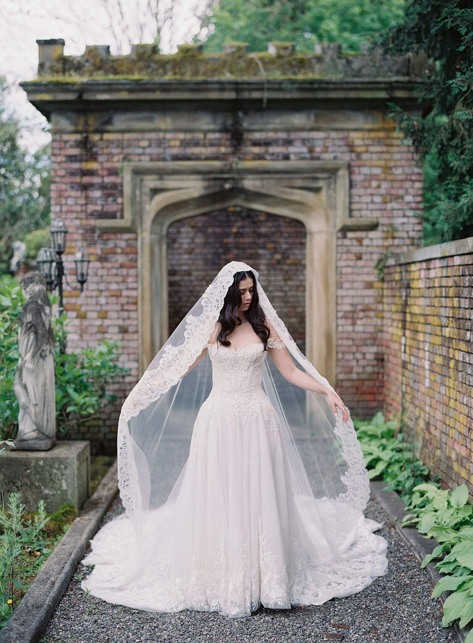 Bride lifts mantilla lace cathedral veil in Ines di Santo gown in Thornewood Castle garden - Jacqueline Benét Photography