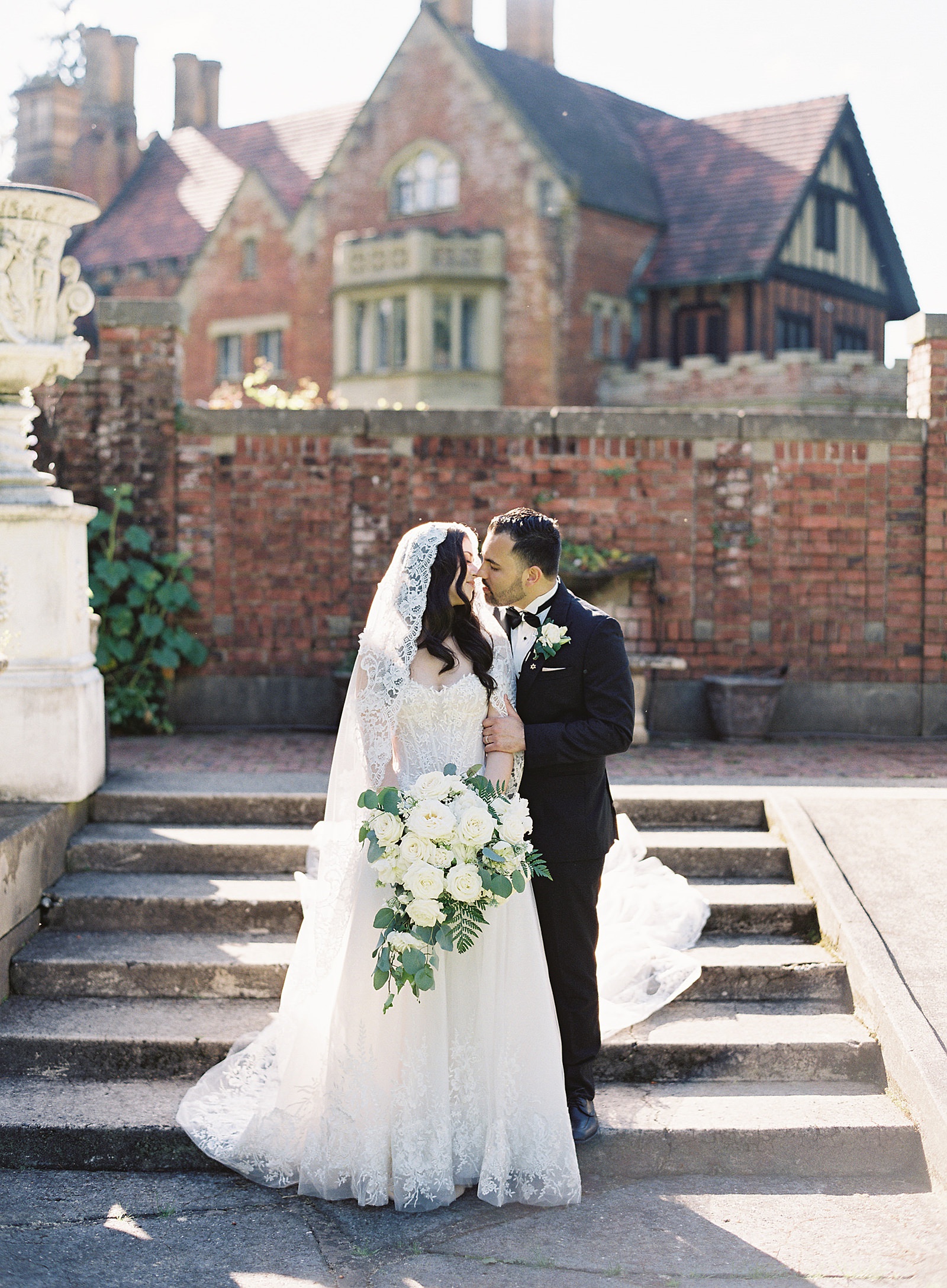 Bride and groom kiss on the steps in front of Thornewood Castle - Jacqueline Benét Photography