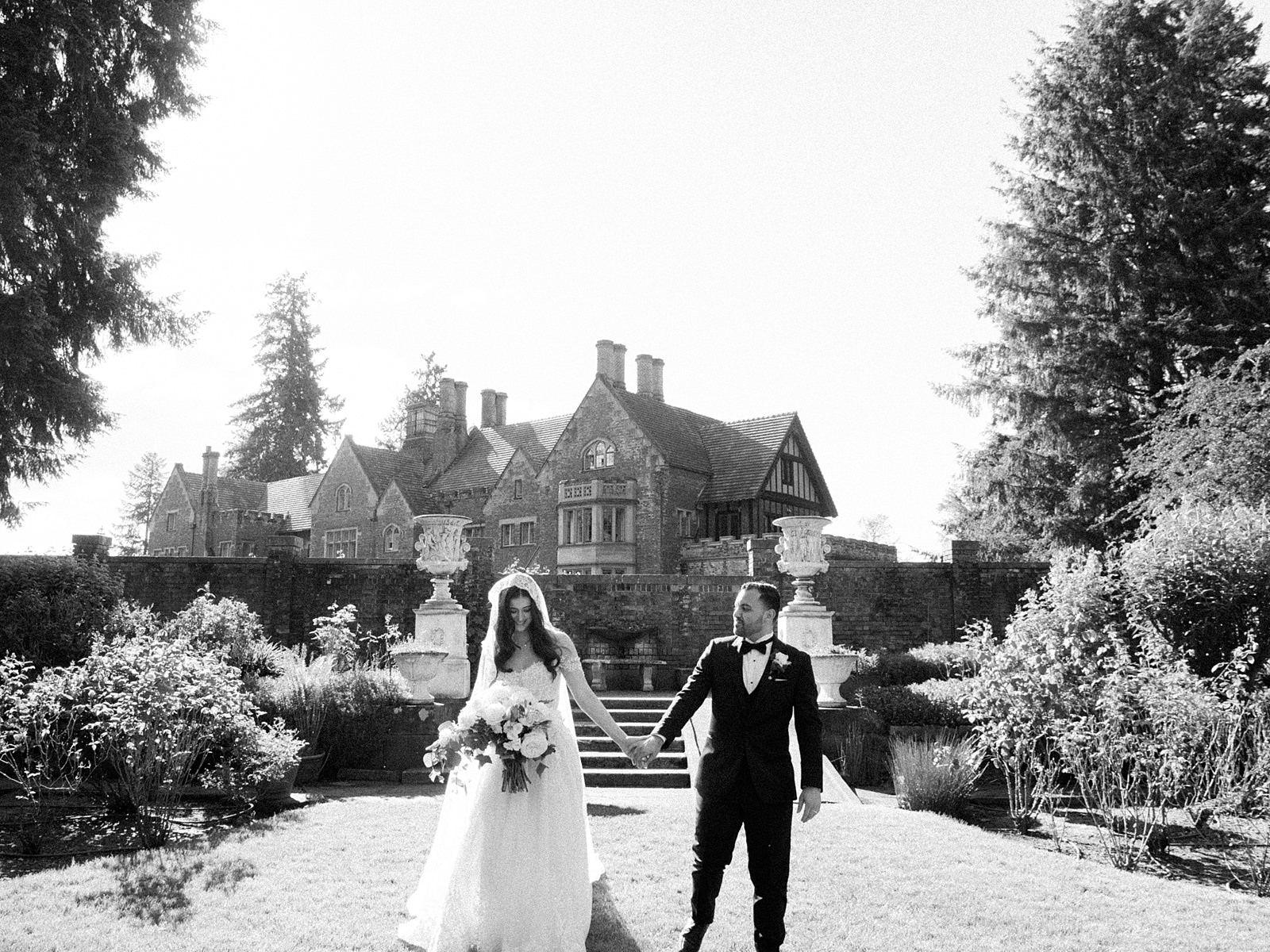 Bride and groom walk in garden in front of Thornewood Castle - Jacqueline Benét Photography