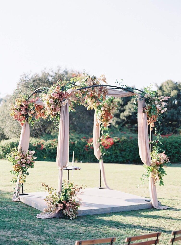 Pink and mauve floral chuppah with pink drapery at Rancho Valencia wedding ceremony - Jacqueline Benet Photography
