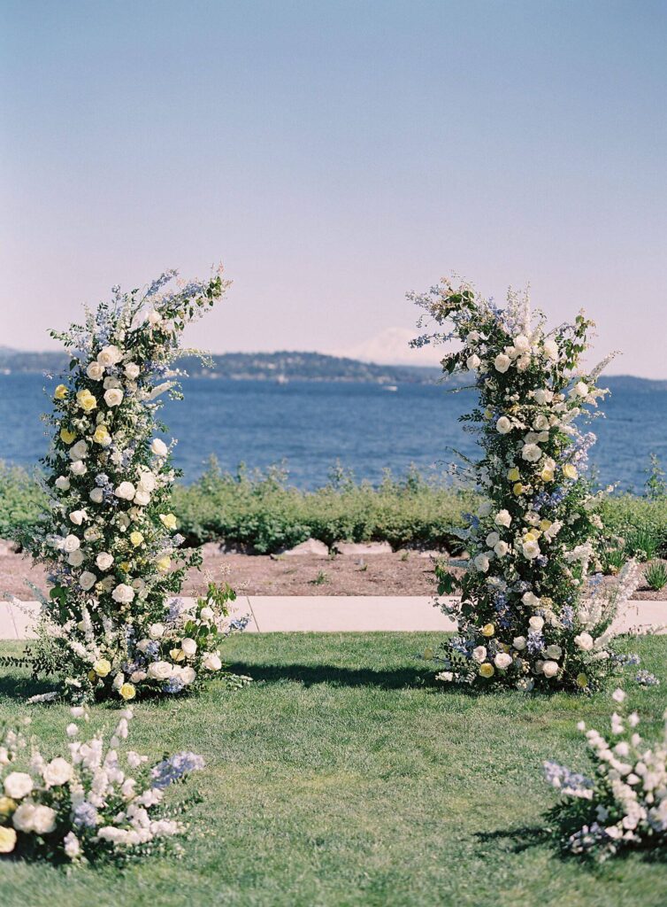 White pale blue and pastel yellow floral arch open top at Seattle Tennis Club overlooking the lake and Mount Rainier - Jacqueline Benet Photography | Seattle wedding photorapher