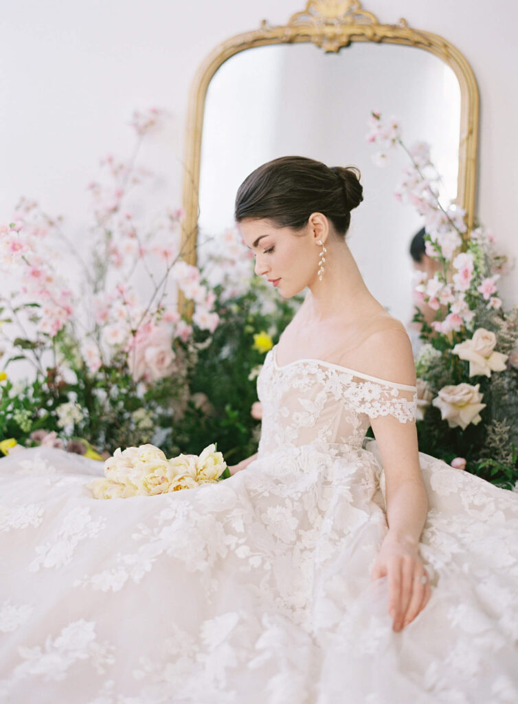 Photo of bride looking looking down with flowers and mirror behind her on Contax 645 camera in lace gown, photo by Jacqueline Benet Photography
