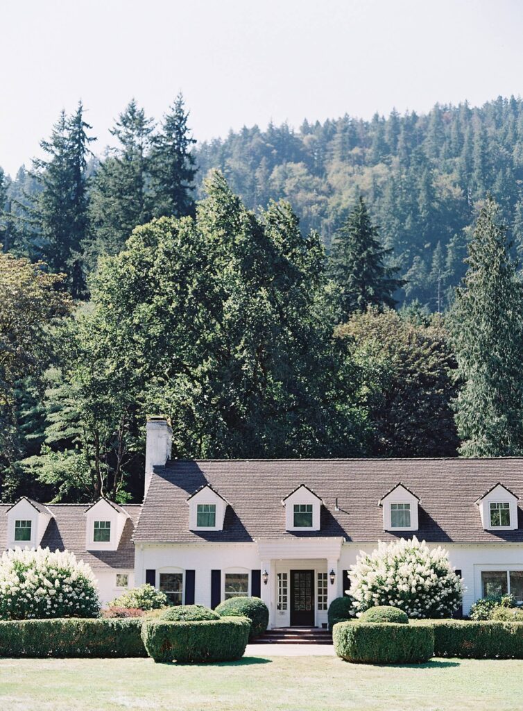 Fox Hollow Farm white manor home in Seattle with tall pine trees and white hydrangeas - Jacqueline Benét Photography
