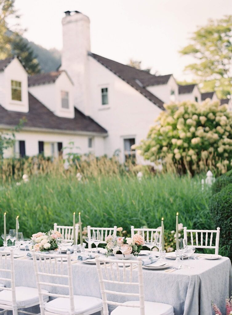 Wedding reception in pale blue and blush with white chivari chairs with Fox Hollow Farms white manor home in the background and hydrangeas - Jacqueline Benét Photography