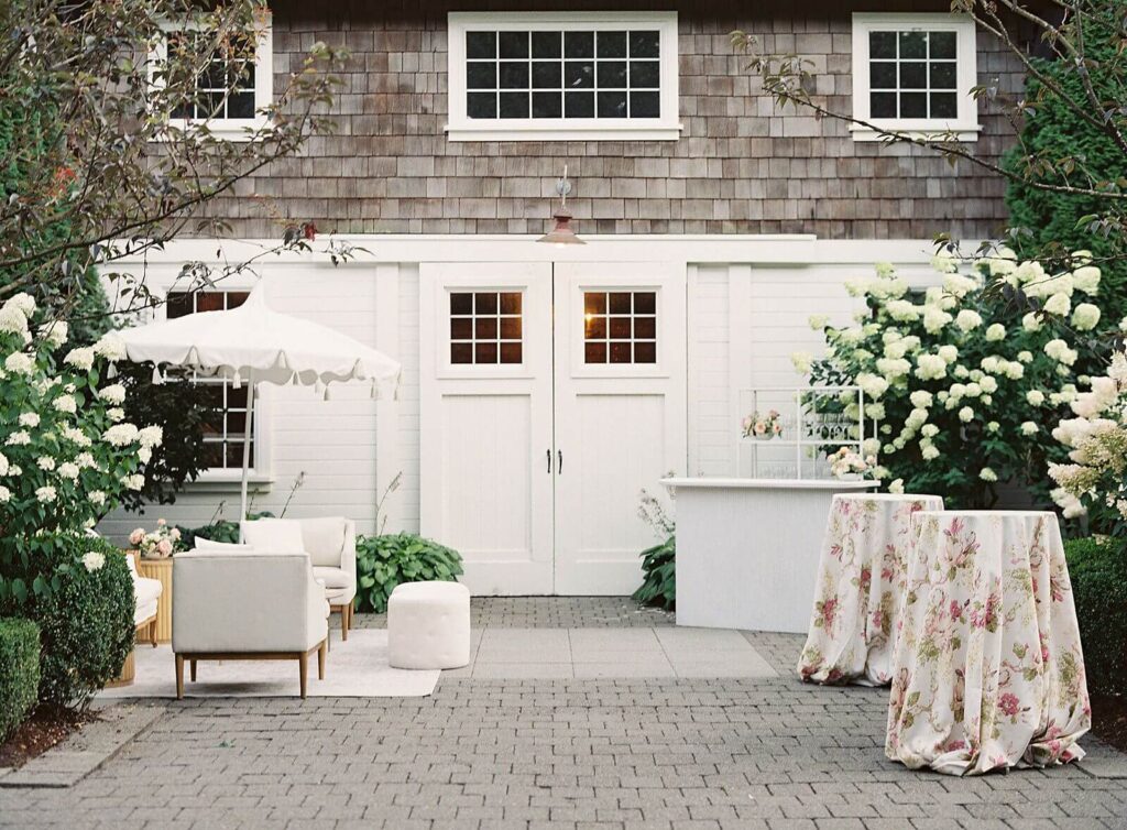 Hamptons coastal wedding reception with cocktail hour in front of white hydrangeas and floral tablecloth - Jacqueline Benét Photography