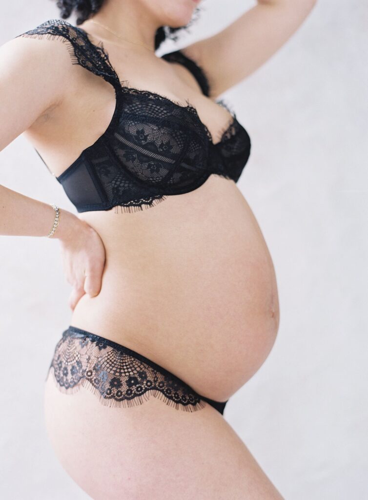 woman in black lace showing pregnant belly in maternity boudoir photoshoot in Seattle