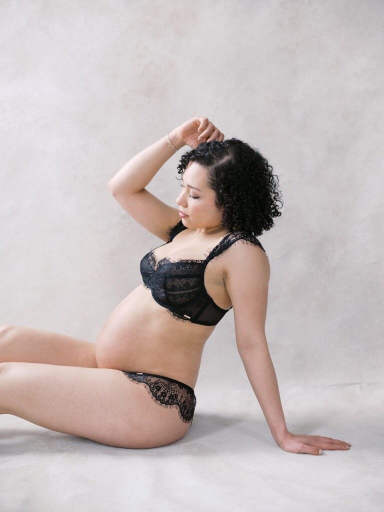 woman in black lace showing pregnant belly in maternity boudoir photoshoot in Seattle