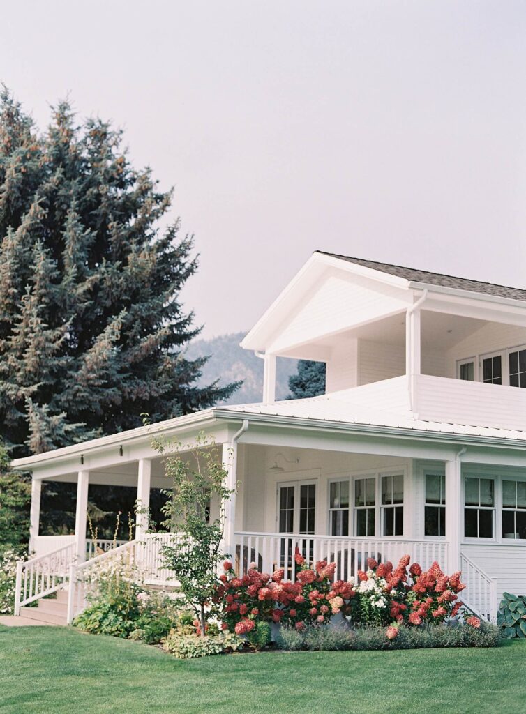 Charming white farmhouse-style venue surrounded by blooming hydrangeas and mountain views at Harmony Meadows wedding venue.