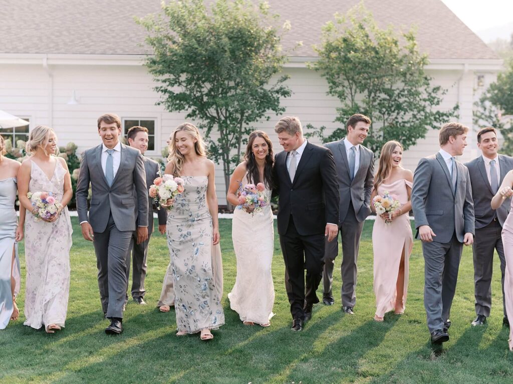 Bride and groom walking with their wedding party on the lawn outside the venue during a joyful Harmony Meadows wedding celebration.