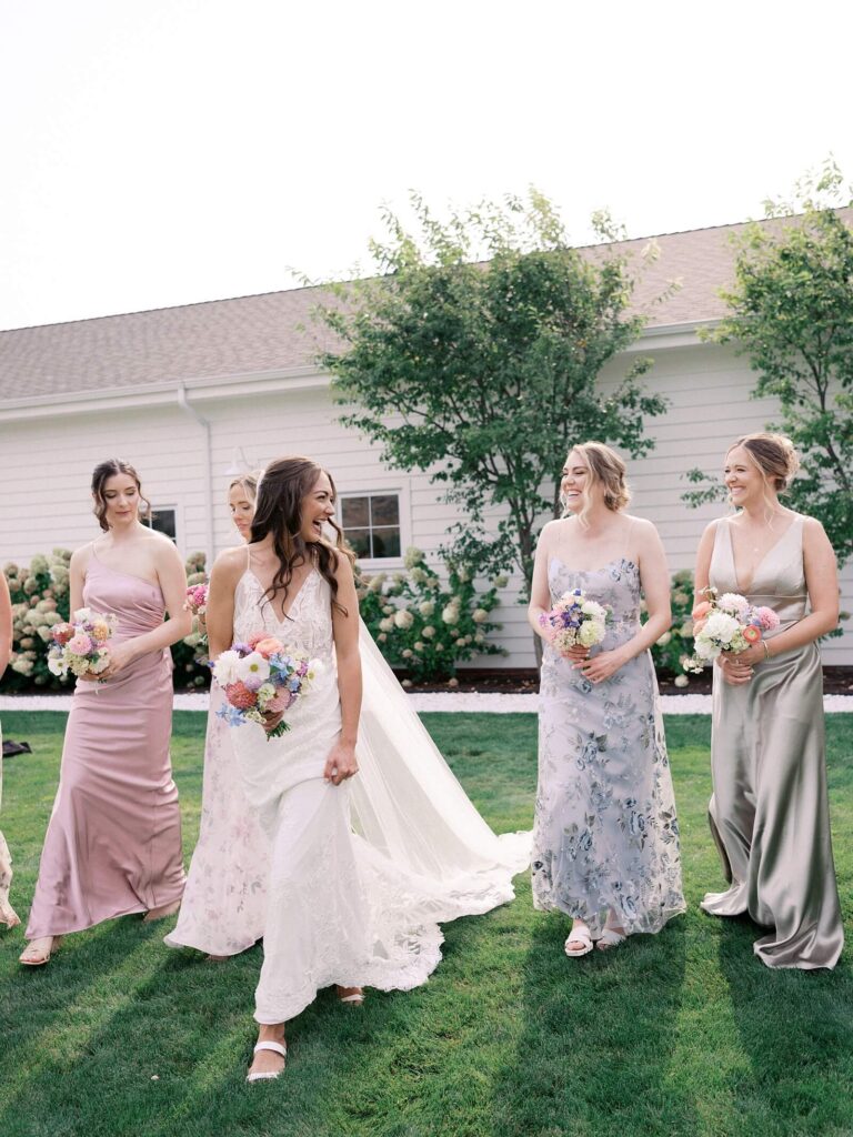 Bride walking with bridal party party on the lawn outside the venue during a joyful Harmony Meadows wedding celebration.