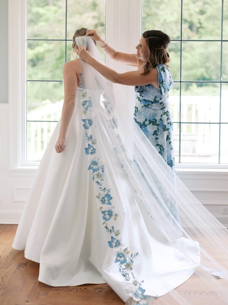 The brides mother helping her put on her wedding veil lined in beautiful blue florals before her garden wedding at fox hollow farm in Seattle. Photo by Jacqueline Benét - Seattle wedding photography