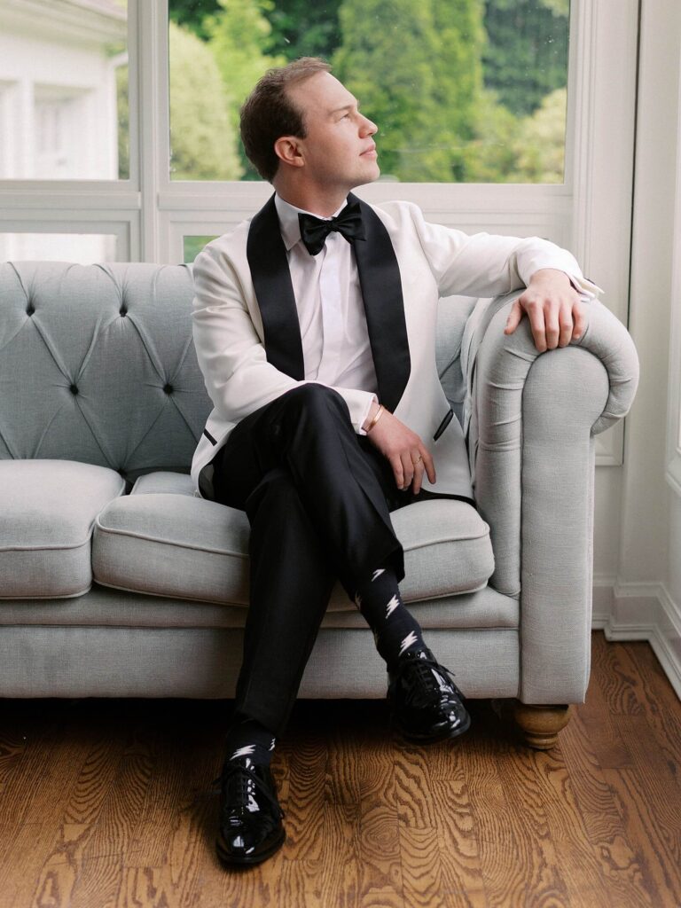 The groom in a white jacket and black bow tie waiting for the moment he first gets to see his bride, captured with timeless elegance by Jacqueline Benét | Fox Hollow Farm wedding