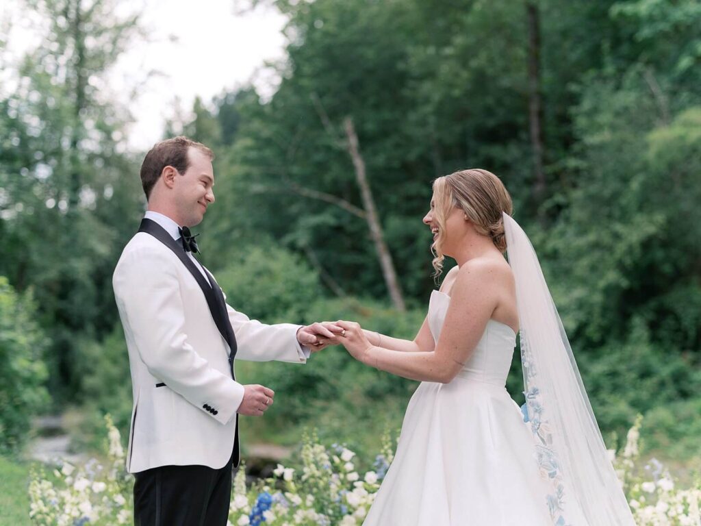 Bride and Groom exchanging vows beneath lush greenery and pastel blooms during their Fox Hollow Farm wedding ceremony, photographed by Jacqueline Benét | Seattle wedding photography