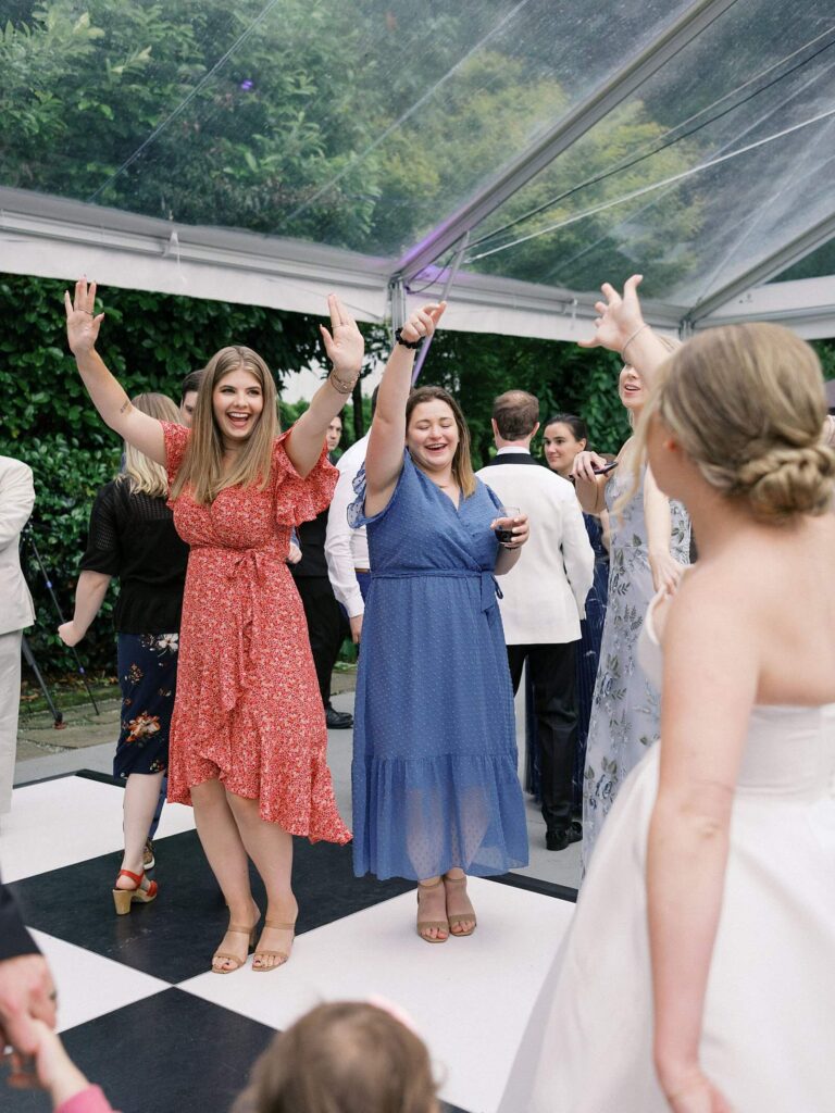 The bride and wedding guests dancing together on the black checkered dance floor at an outdoor wedding at Fox Hollow Farm. Seattle wedding photography 