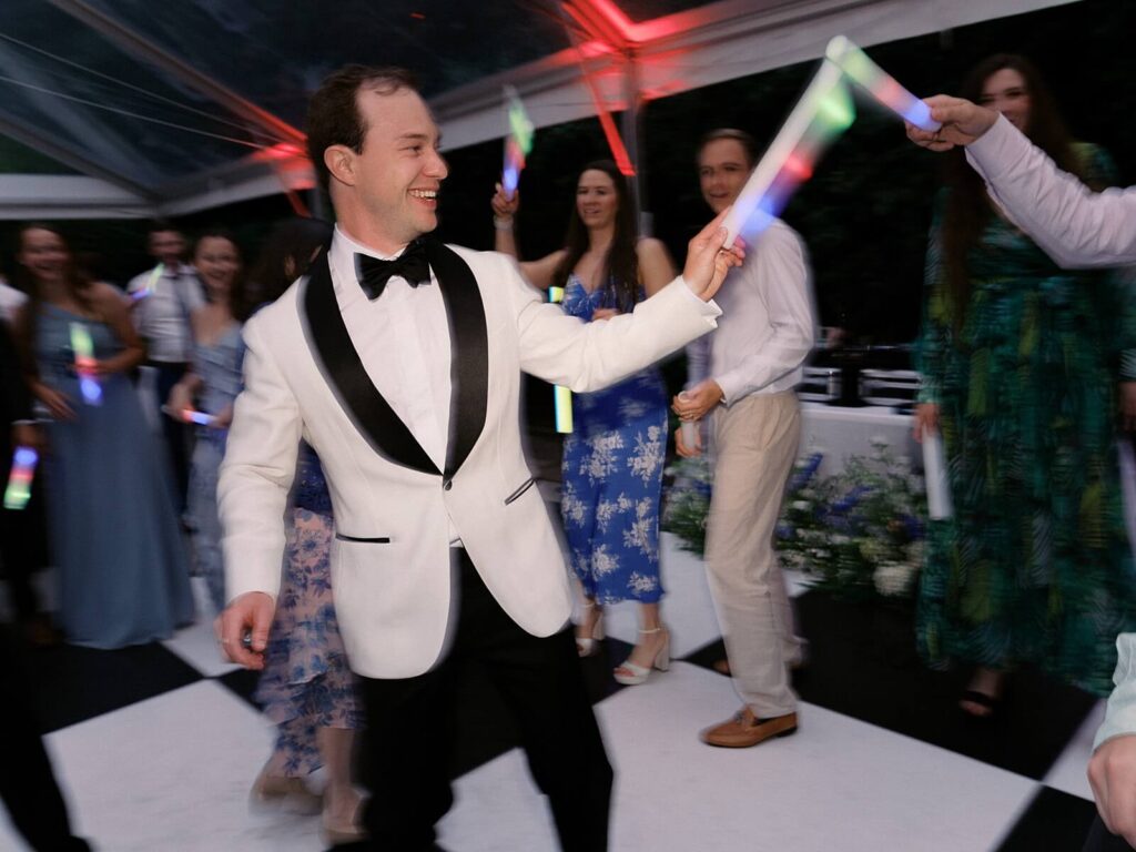 Guests dancing with glow sticks on the checkered dance floor during a lively Fox Hollow Farm wedding reception, captured by Jacqueline Benét | Seattle wedding photography