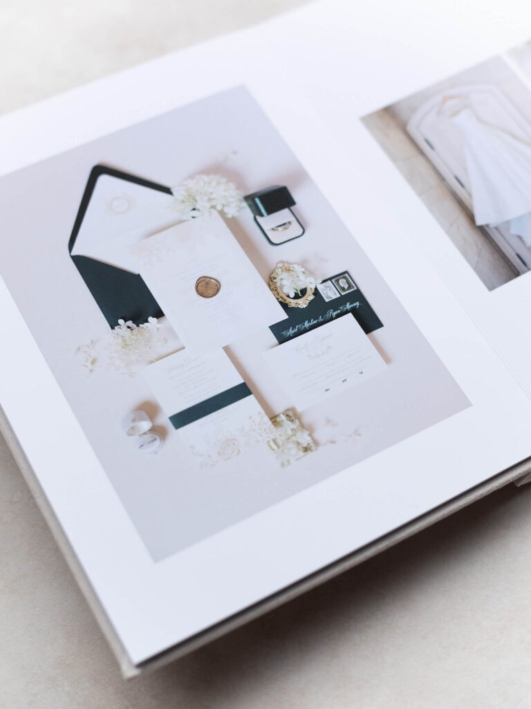 Photo of a classic heirloom wedding photo album opened up to a portrait of a flat lay of the wedding invitations for a Seattle wedding. Captured by Seattle wedding photographer, Jacqueline Benét